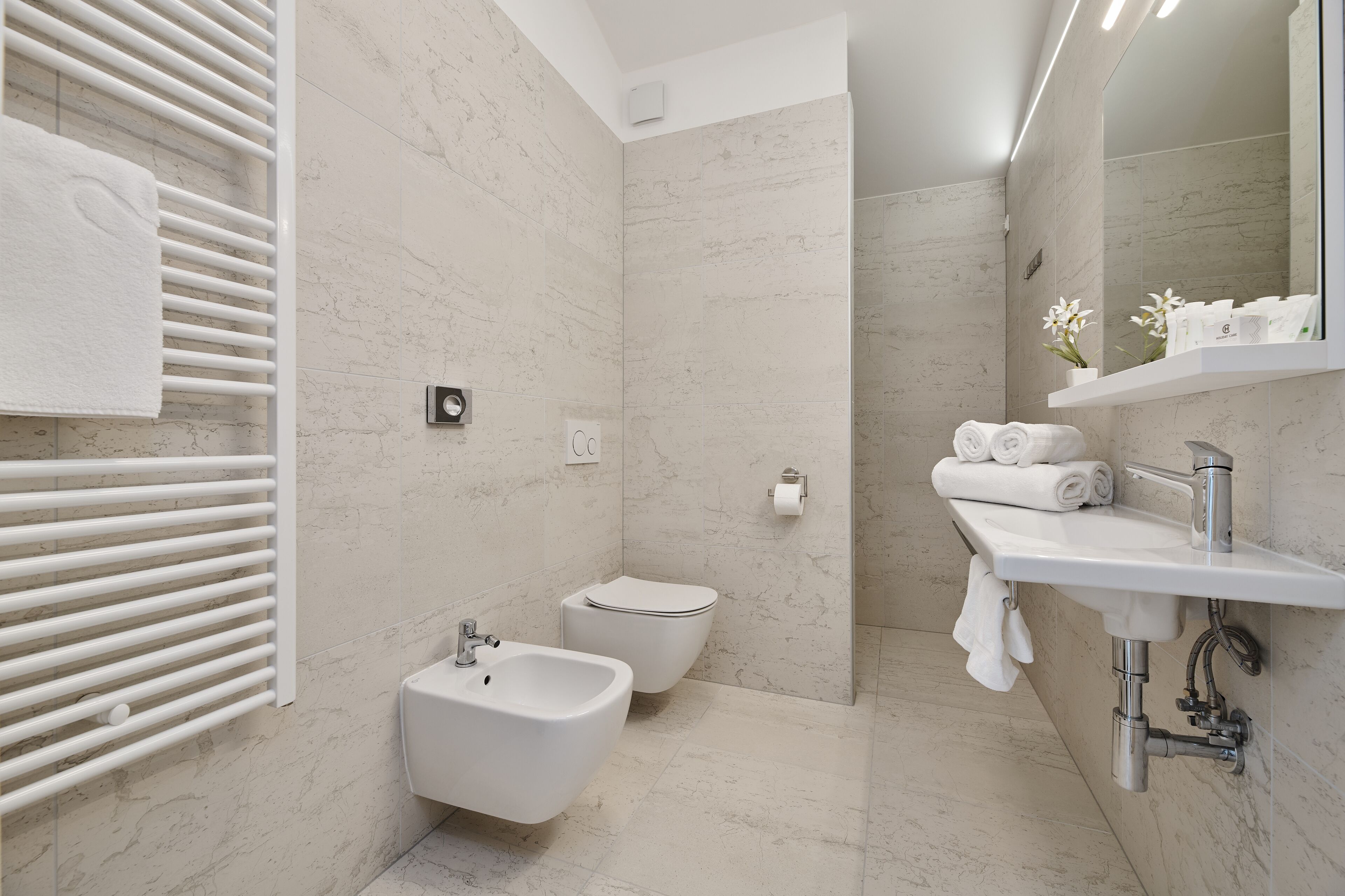 Un baño moderno con bidé, inodoro y lavamanos con espejo.