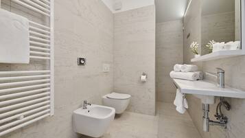 Un baño moderno con bidé, inodoro y lavamanos con espejo.