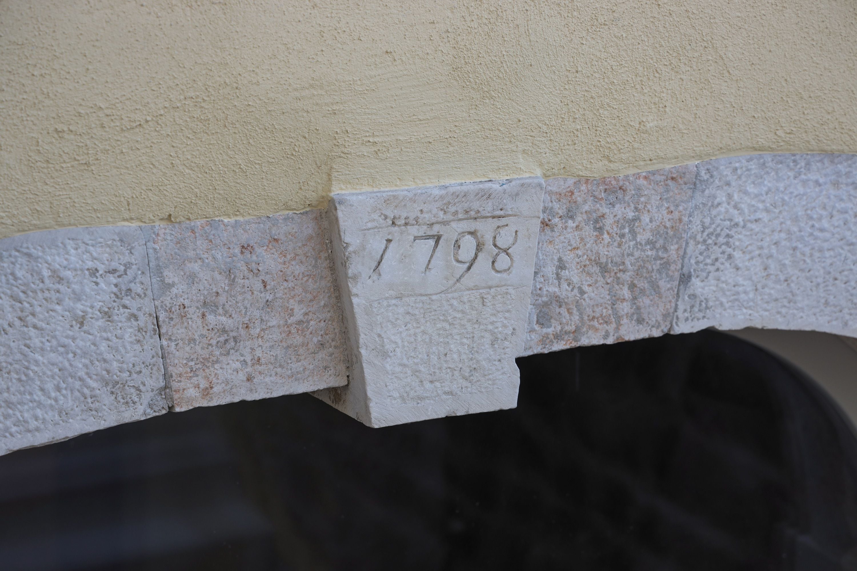 A close-up of a wall with a number plaque '1798' attached to it.
