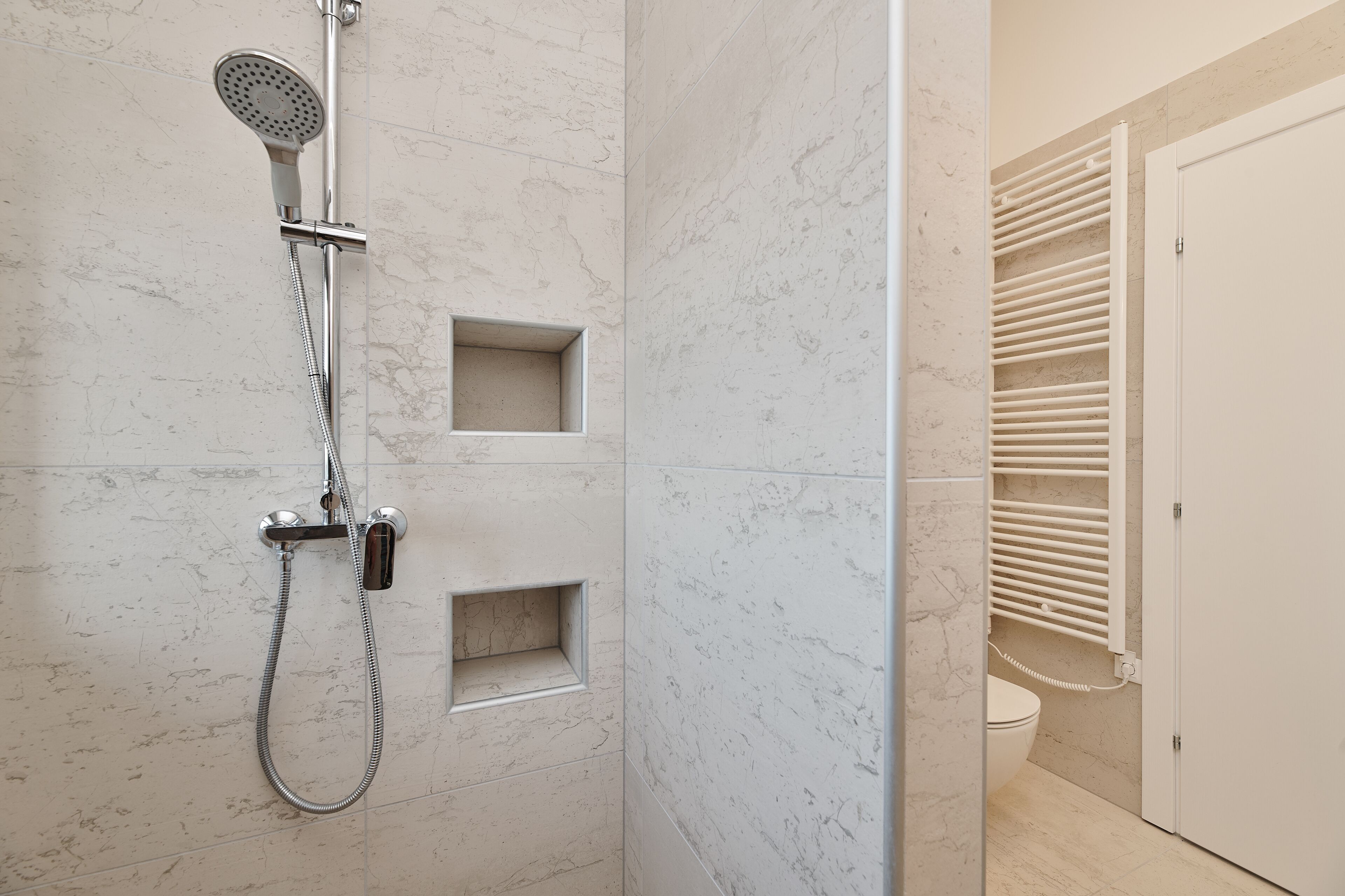 A modern bathroom with a shower, toilet, and built-in storage.