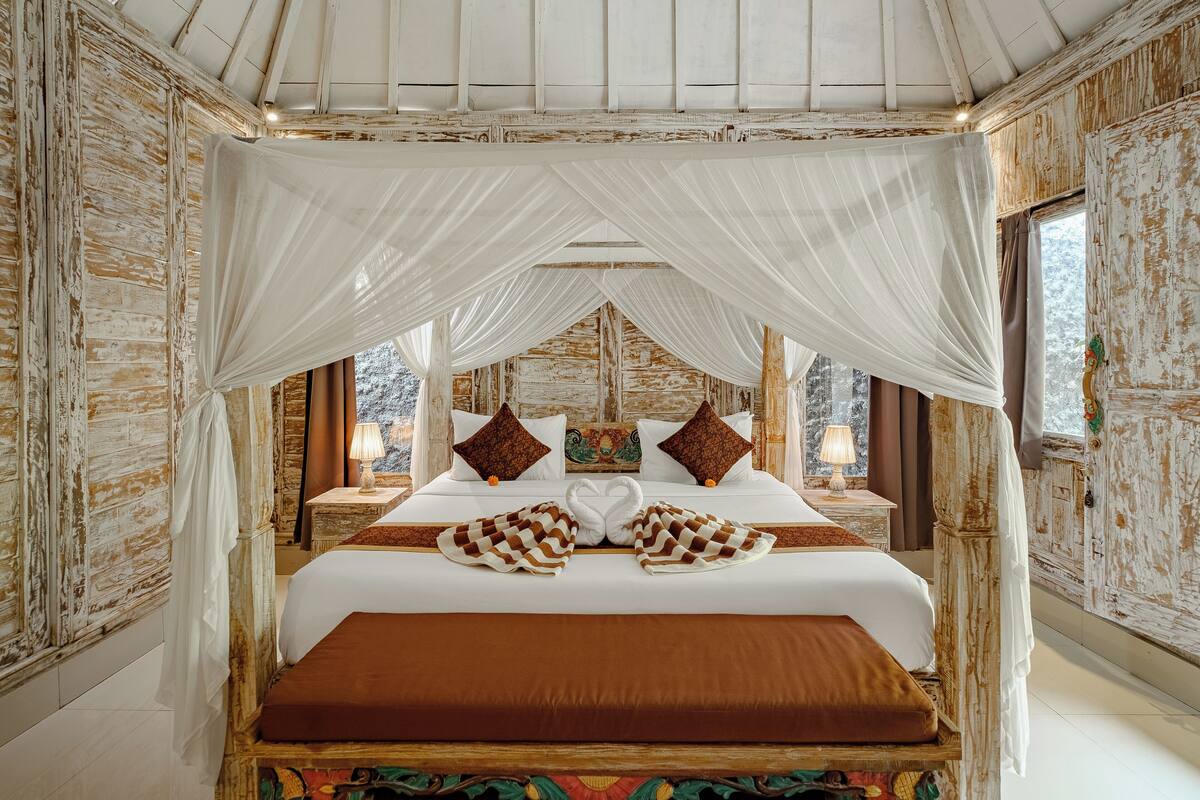 A bed with a canopy, two nightstands, a decorative pillow, and a wall with a rustic finish.