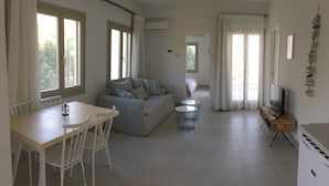 Un salón amplio con sofá, mesa de comedor y mueble para la televisión.