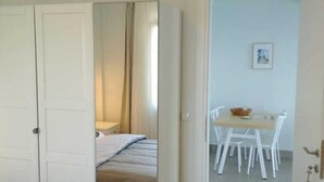 Una habitación de hotel con cama, un baño con espejo y una zona de comedor con mesa y sillas.