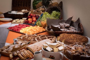 Una mesa de buffet con diversas frutas, pasteles y postres.