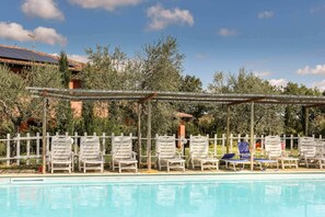 Zona de piscina con sillones de descanso y una pérgola.