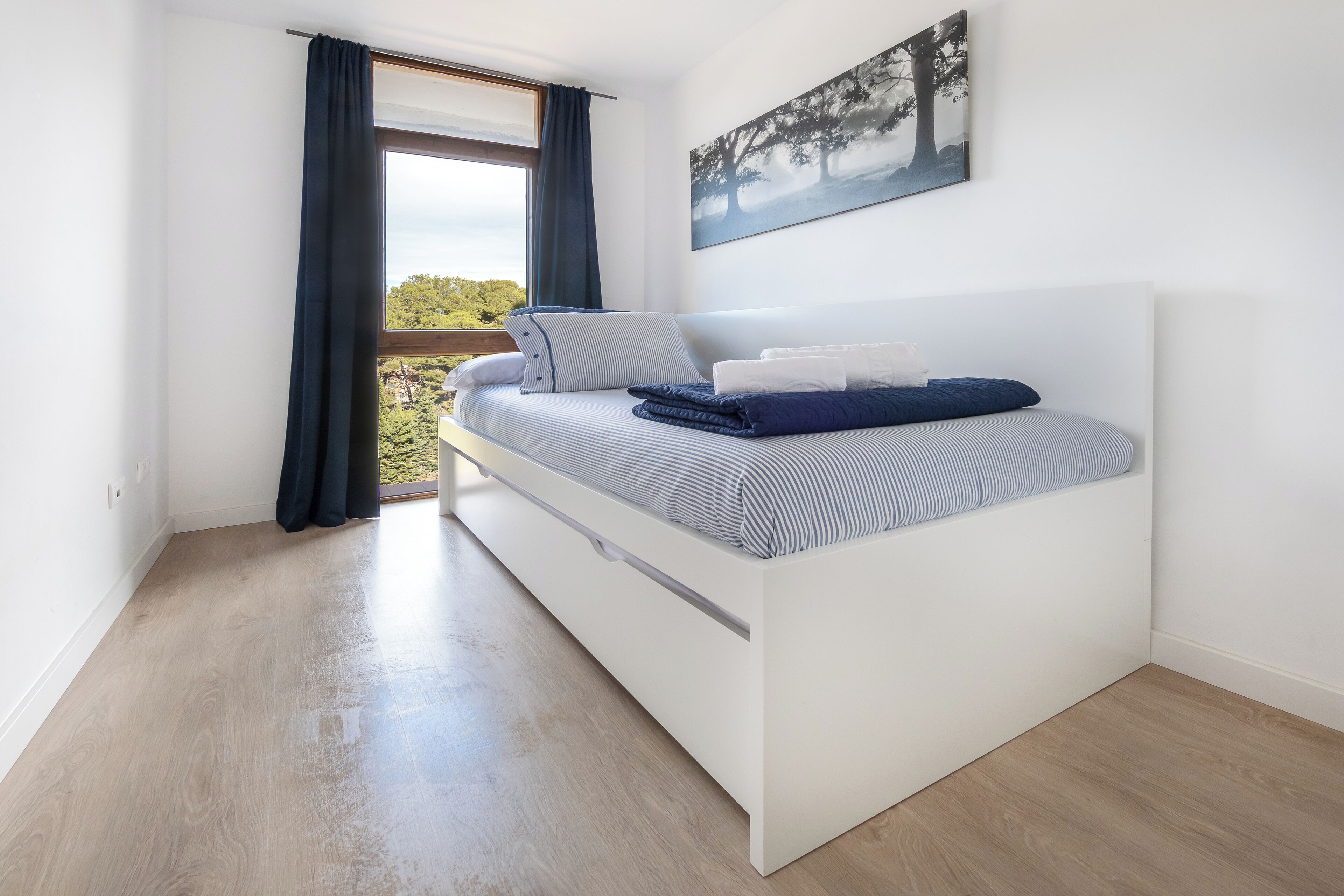 Un dormitorio moderno con cama, ventana con cortinas y un cuadro en la pared.