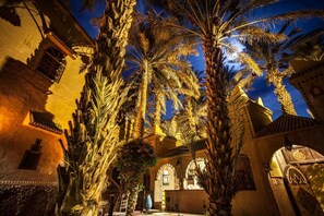 A courtyard with palm trees, a fountain, and traditional architecture.