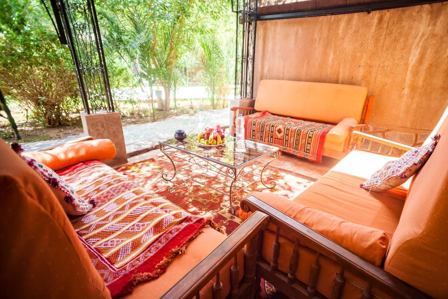 Una zona de estar exterior acogedora con un sofá y una mesa, rodeada por un tapete estampado y una mesa de centro de vidrio.