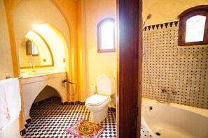A bathroom with a checkered floor, a white toilet, a bathtub, and a shower.