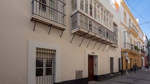 Un edificio con varios balcones, una puerta y una calle estrecha.