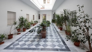 Un pasillo con suelo de cuadros, paredes blancas y plantas en macetas.