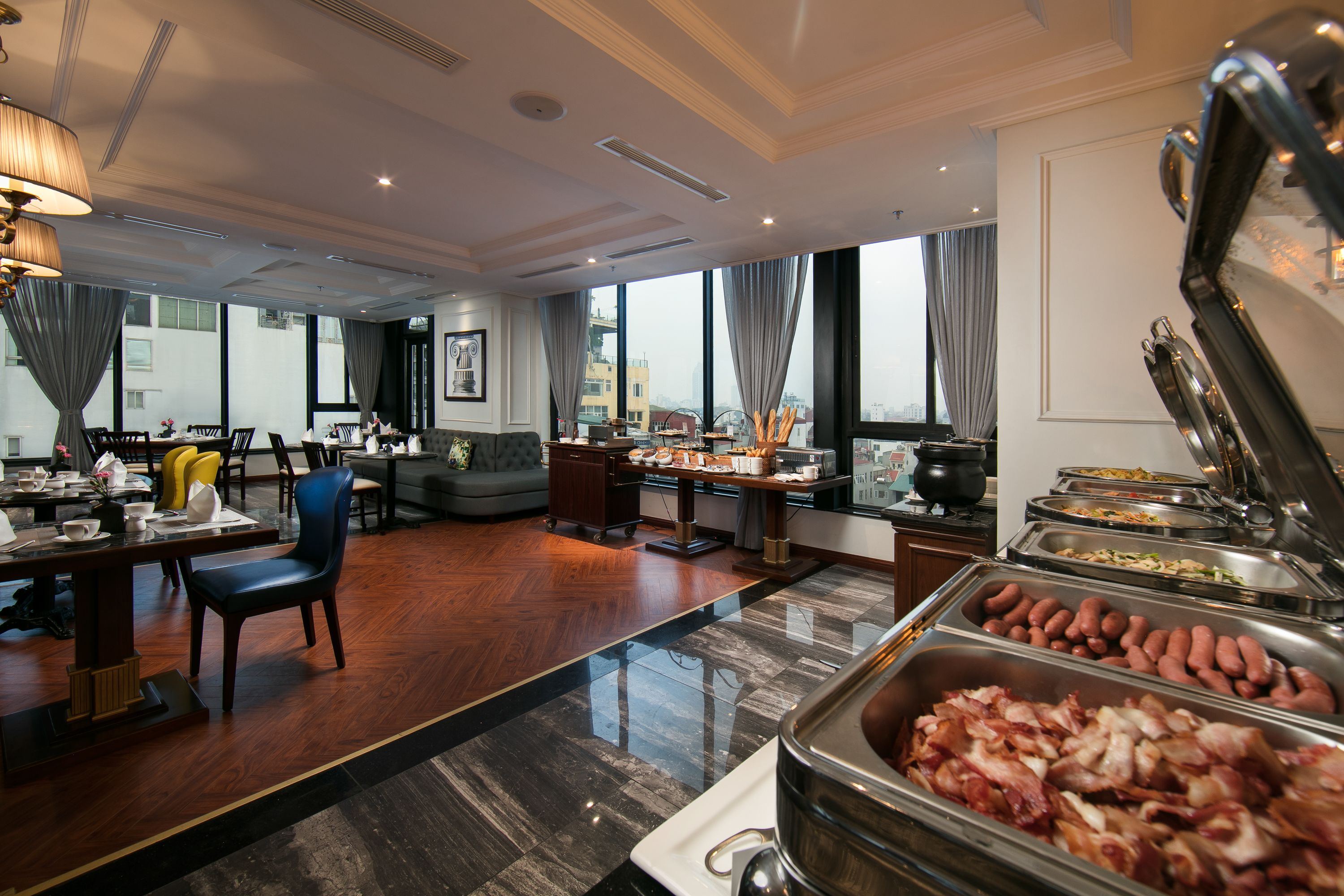 A hotel dining area with buffet, seating, and large windows.