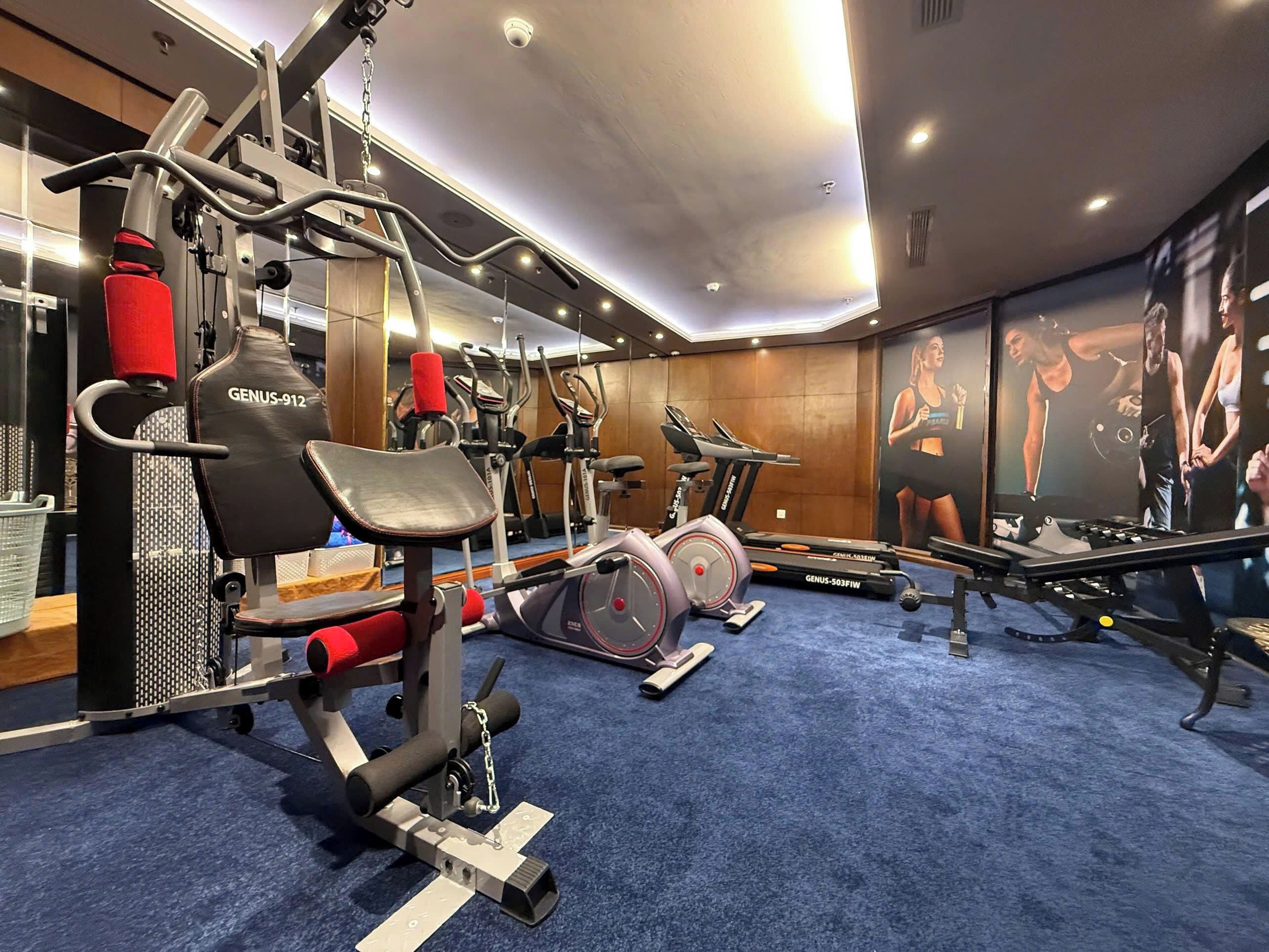 A gym with cardio machines, weightlifting equipment, and a blue carpet.