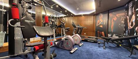 A gym with cardio machines, weightlifting equipment, and a blue carpet.