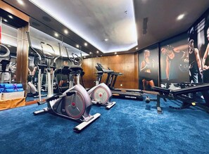 A gym with cardio equipment, weight machines, and a mirrored wall.
