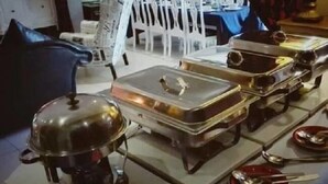Ein reichhaltiges Buffet mit mehreren Servierstationen, jede mit einem abgedeckten Gericht und einem Löffel auf einem Teller.