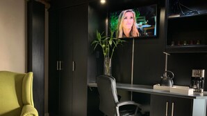 Ein moderner Arbeitsraum mit Schreibtisch, Stuhl, Fernseher und Pflanze.