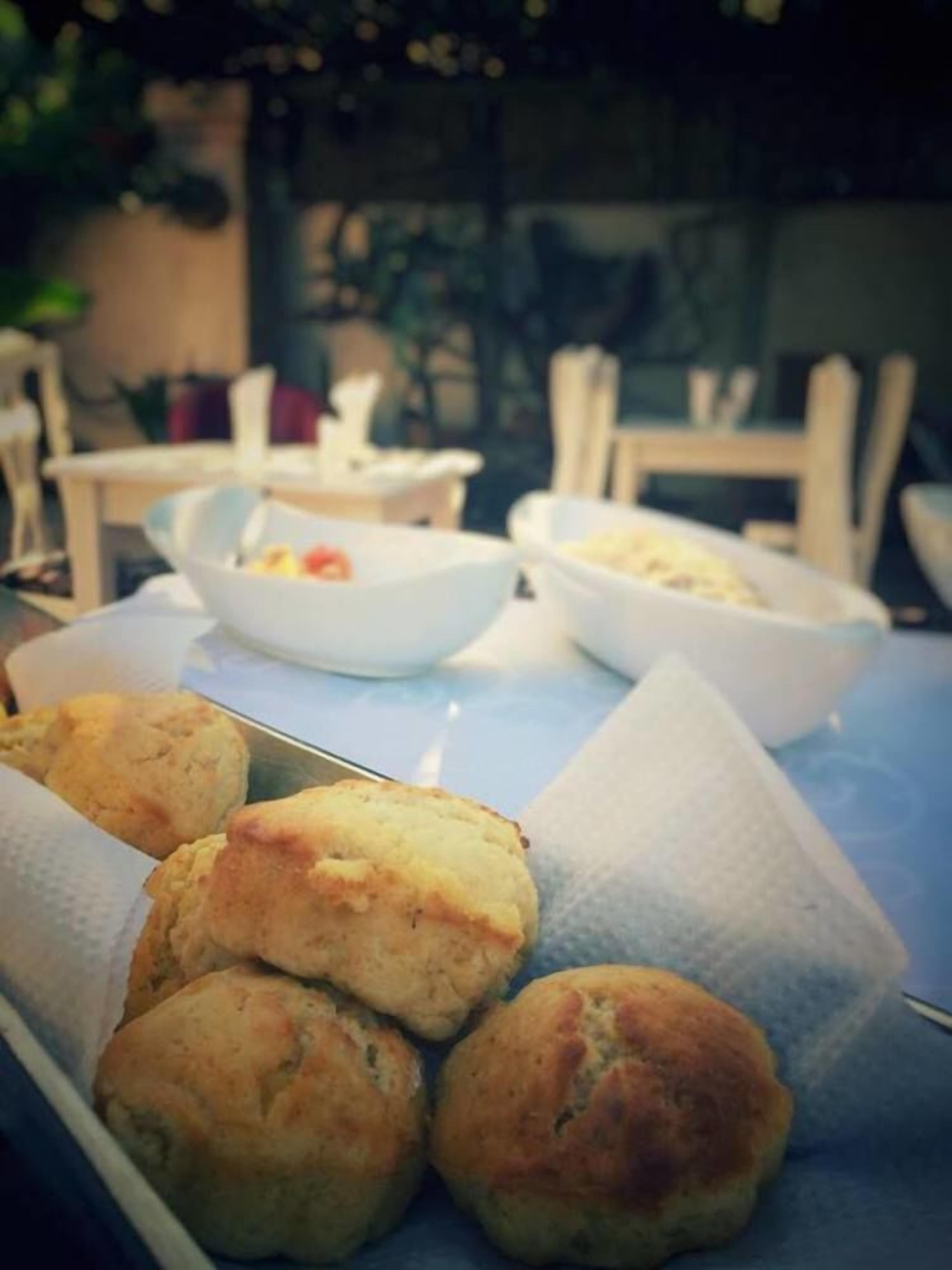 A table with several bowls of food and a tray of biscuits.