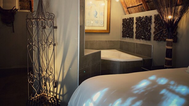 Ein modernes Badezimmer mit einer großen Badewanne, einem dekorativen Metallzaun, einer Holzzieldecke und einer an der Wand befestigten Uhr.