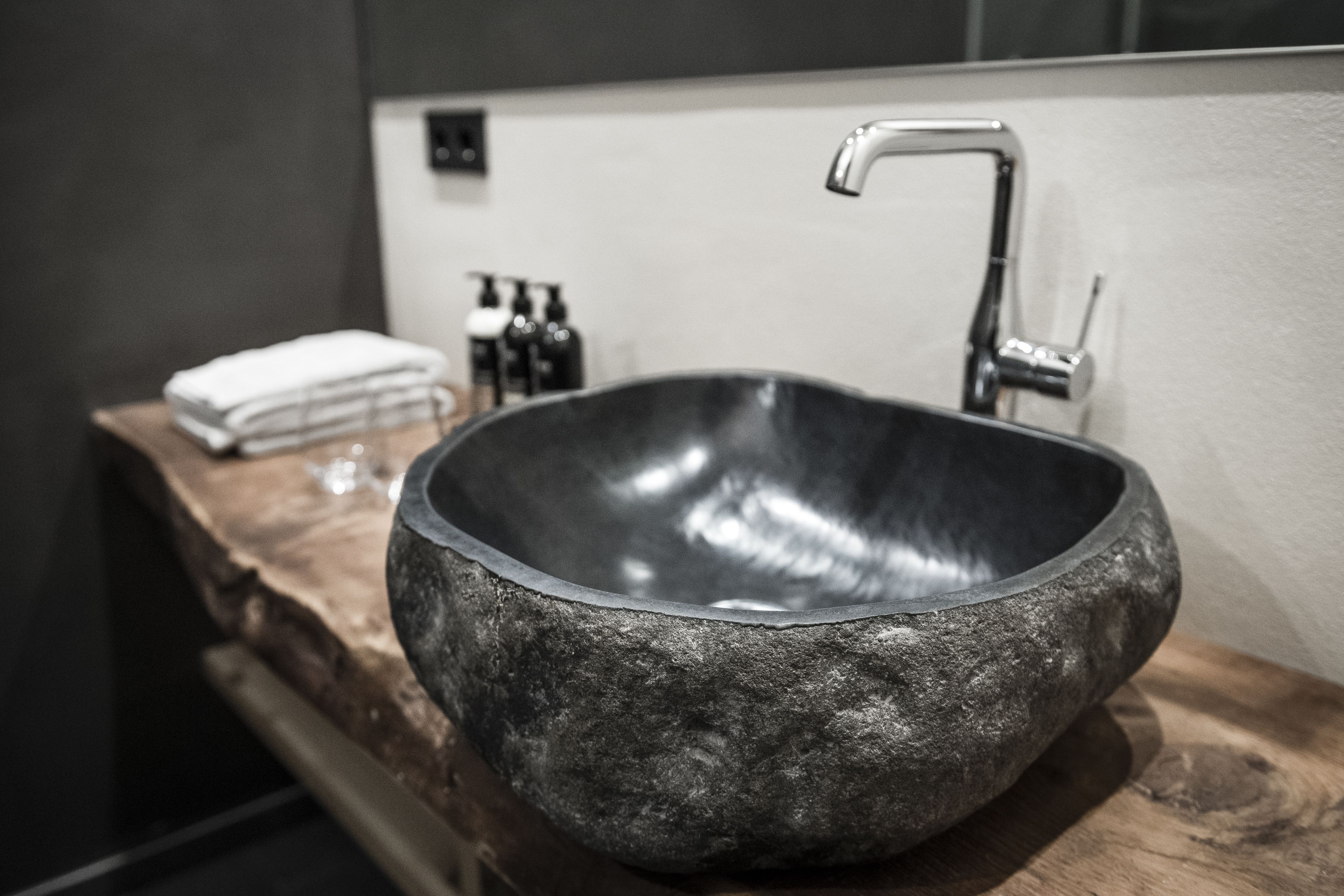A modern bathroom with a large, dark stone sink and a sleek, metallic faucet.