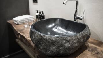 A modern bathroom with a large, dark stone sink and a sleek, metallic faucet.