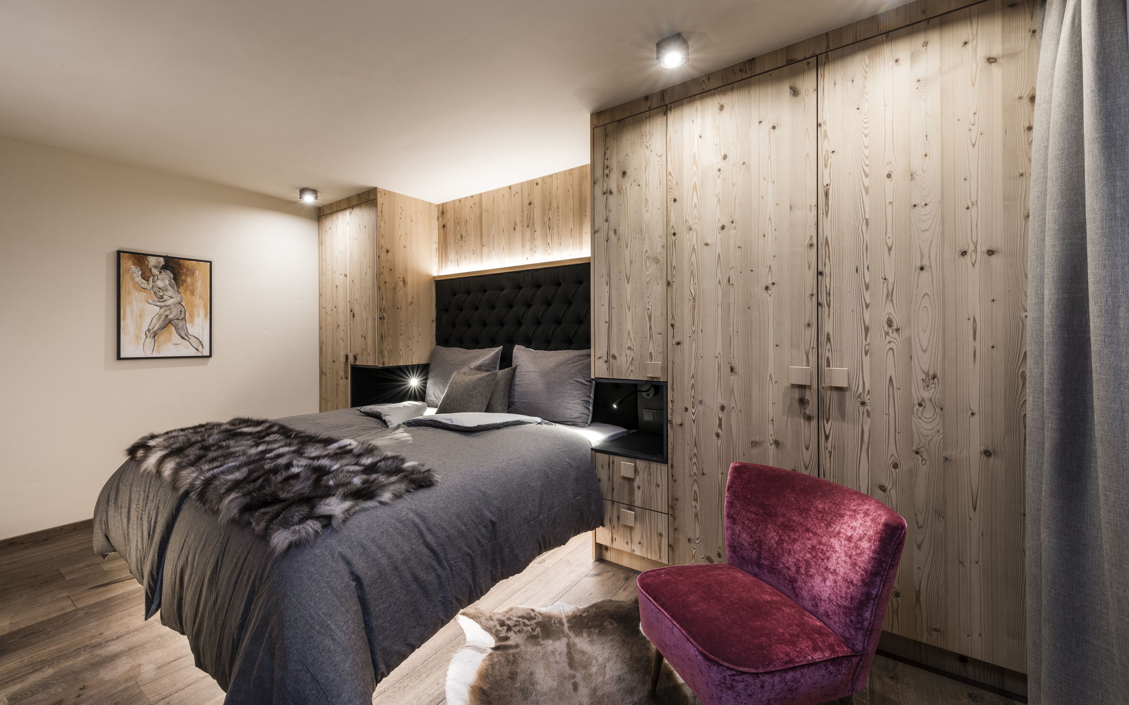 Une chambre moderne avec un grand lit, une armoire en bois et un fauteuil rouge.