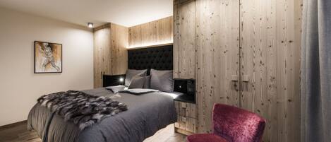 Une chambre moderne avec un grand lit, une armoire en bois et un fauteuil rouge.