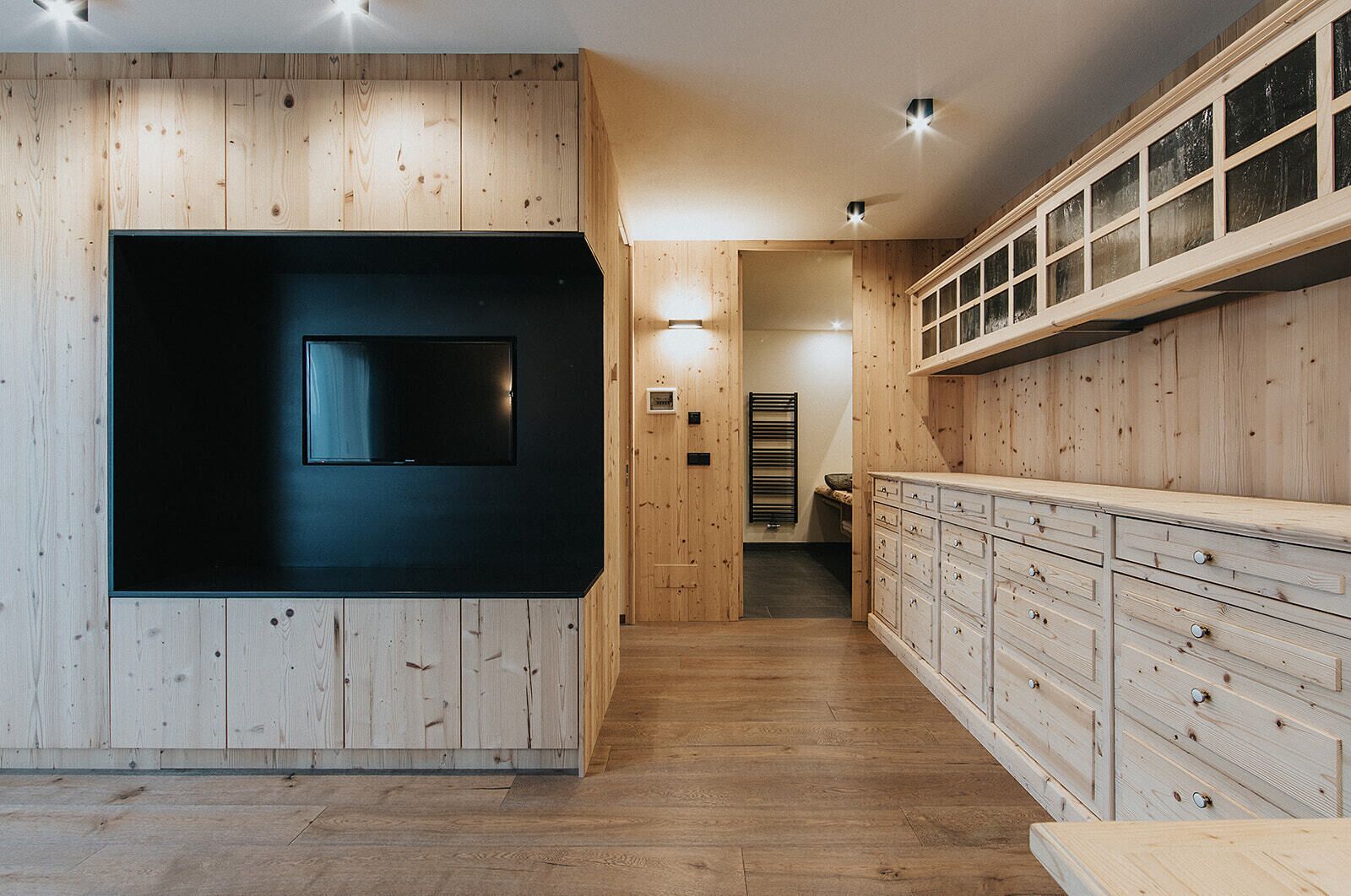 A modern kitchen with wooden paneling, a black countertop, and built-in cabinets.