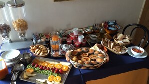 Une table de buffet proposant une variété d’aliments, notamment des fruits, des pâtisseries et des boissons.
