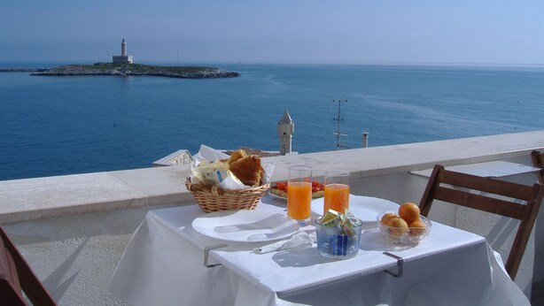 Une table dressée avec des aliments pour le petit-déjeuner et une vue sur la mer.