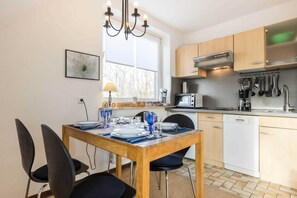 A modern kitchen with wooden cabinets, a dining table set for four, and a window providing natural light.