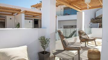 Un espace de détente extérieur moderne, comprenant un canapé, deux fauteuils, une plante en pot et un pouf en fibres tressées.