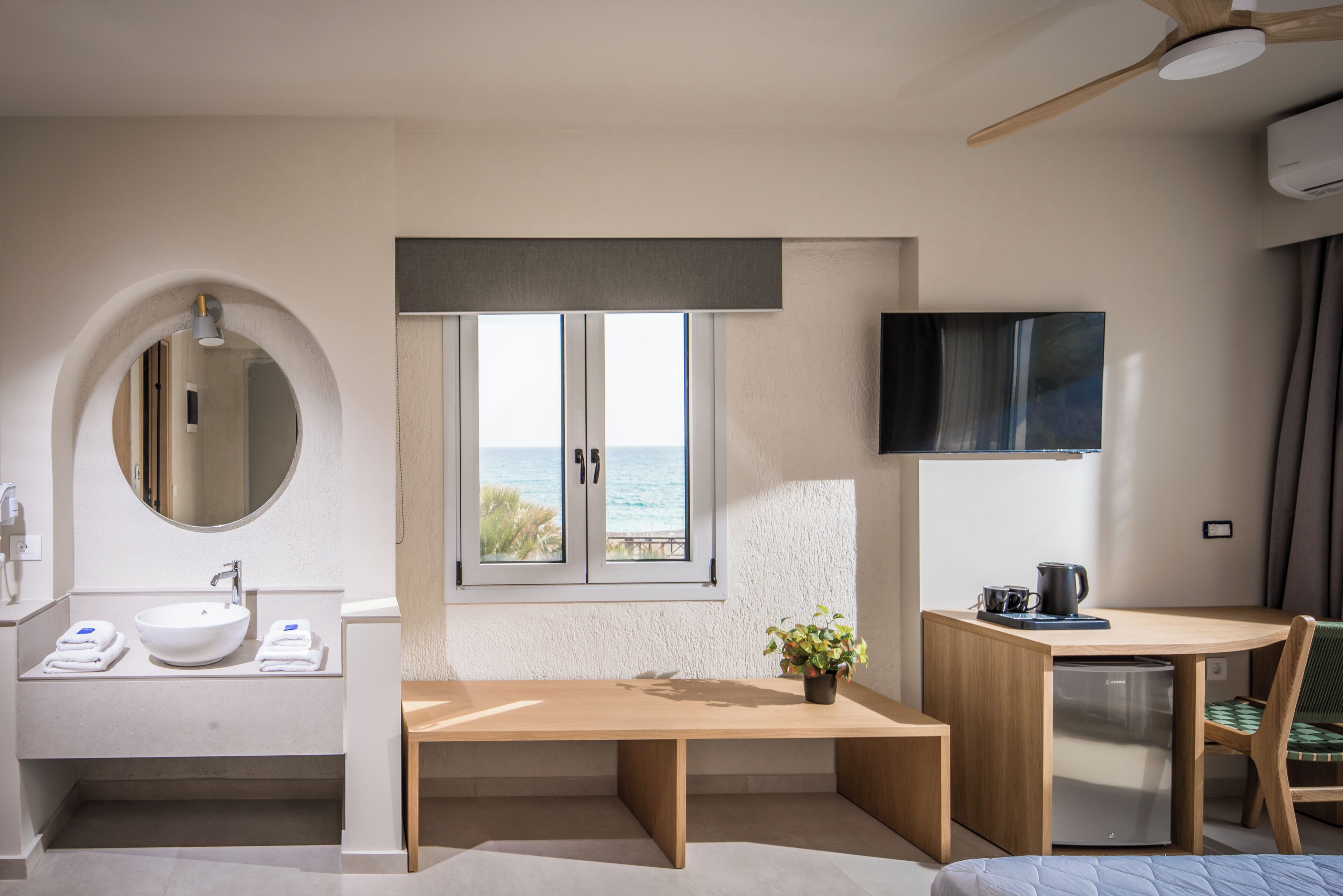 Un bany modern amb un lavabo, un mirall i una finestra amb vista al mar.