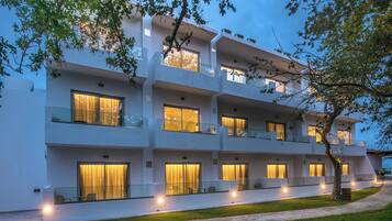 A multi-story hotel with balconies, large windows, and a paved pathway.