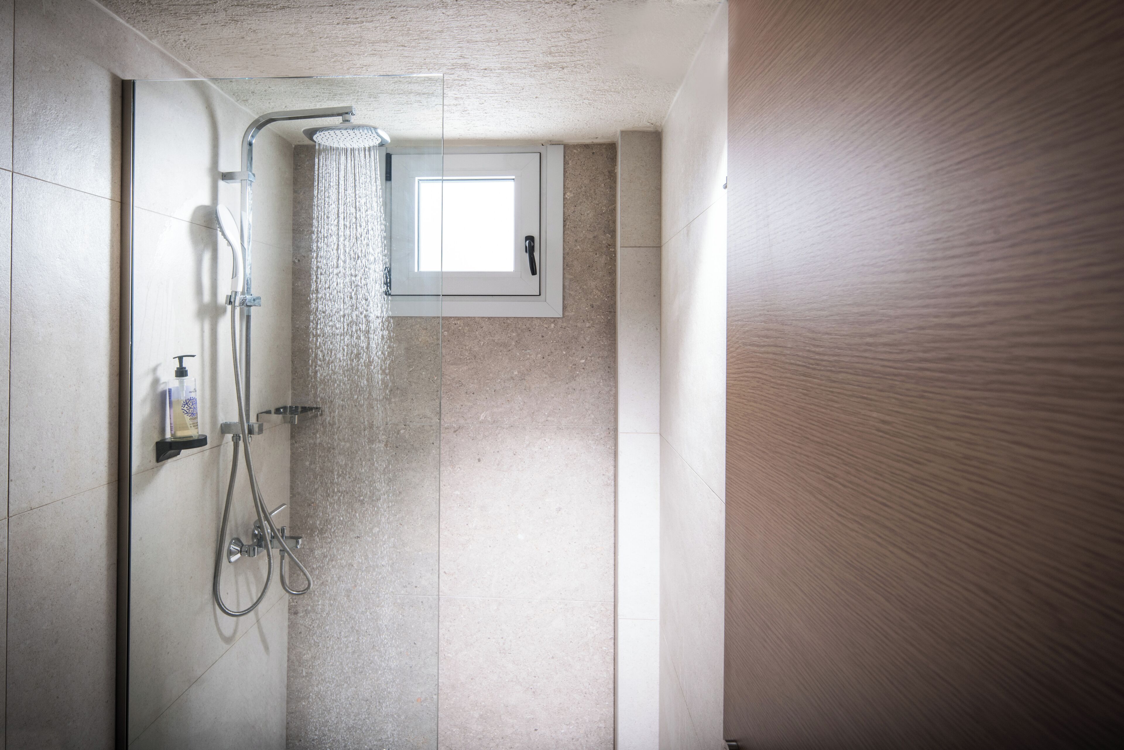 A modern shower with a handheld showerhead and a wall-mounted faucet.