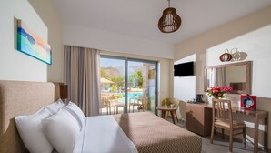 Ein Hotelzimmer mit Bett, Schreibtisch, Stuhl, Fernseher, großem Fenster und Blick auf Pool und Berge.