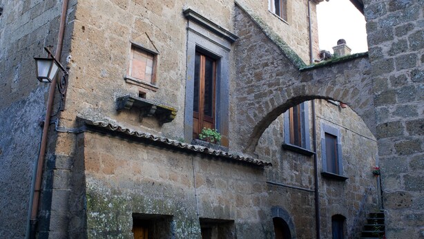 A stone building with a courtyard, a wooden door, and a small window. - Palazzo Contino (Bagnoregio)