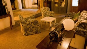 A cozy living room with patterned furniture, a small table, and a decorative item on a bench. - Palazzo Contino (Bagnoregio)