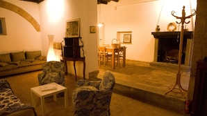 A cozy living room with a sofa, patterned armchairs, a small table, and a fireplace. - Palazzo Contino (Bagnoregio)