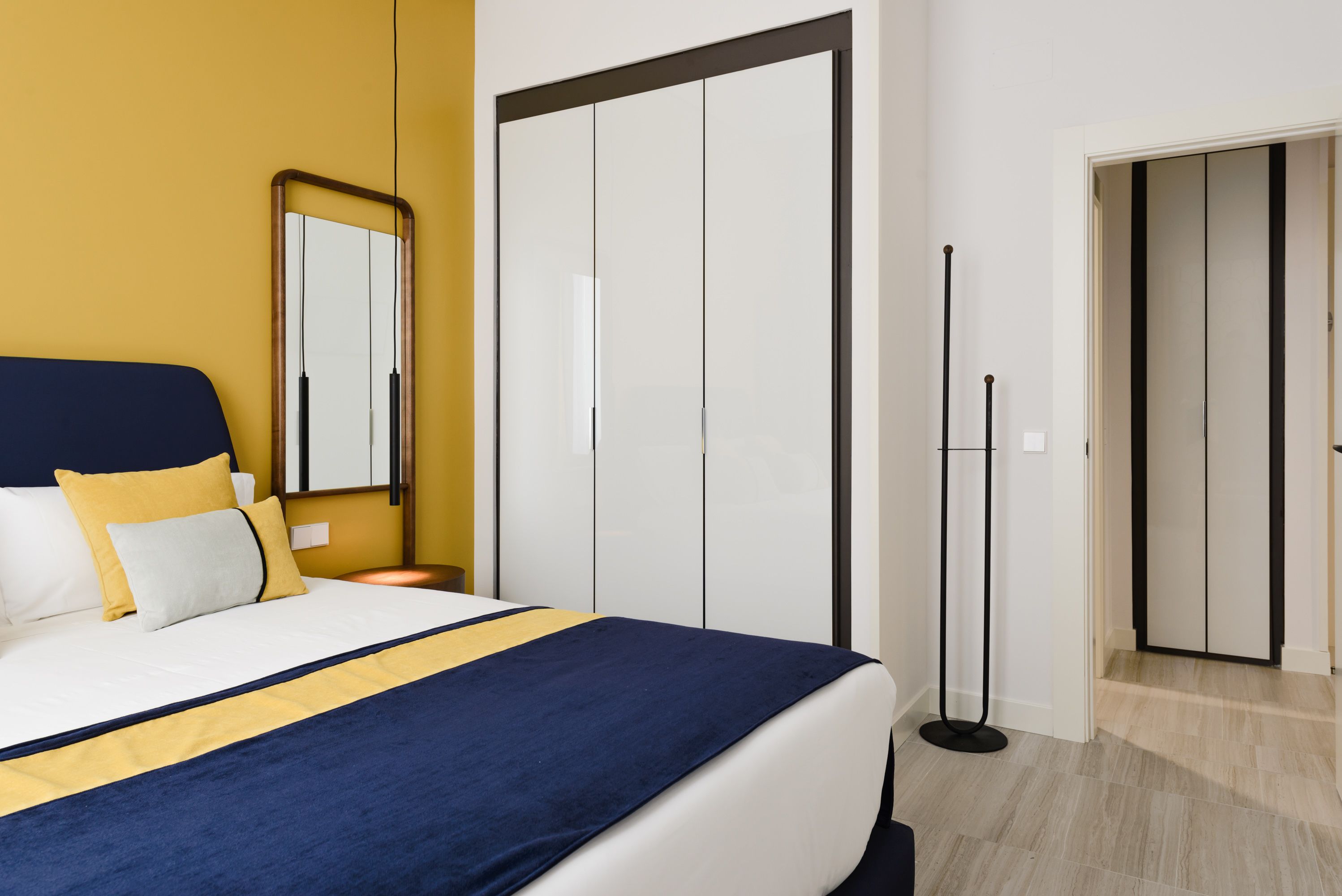 Una habitación de hotel moderna con una cama grande, un armario y un espejo.