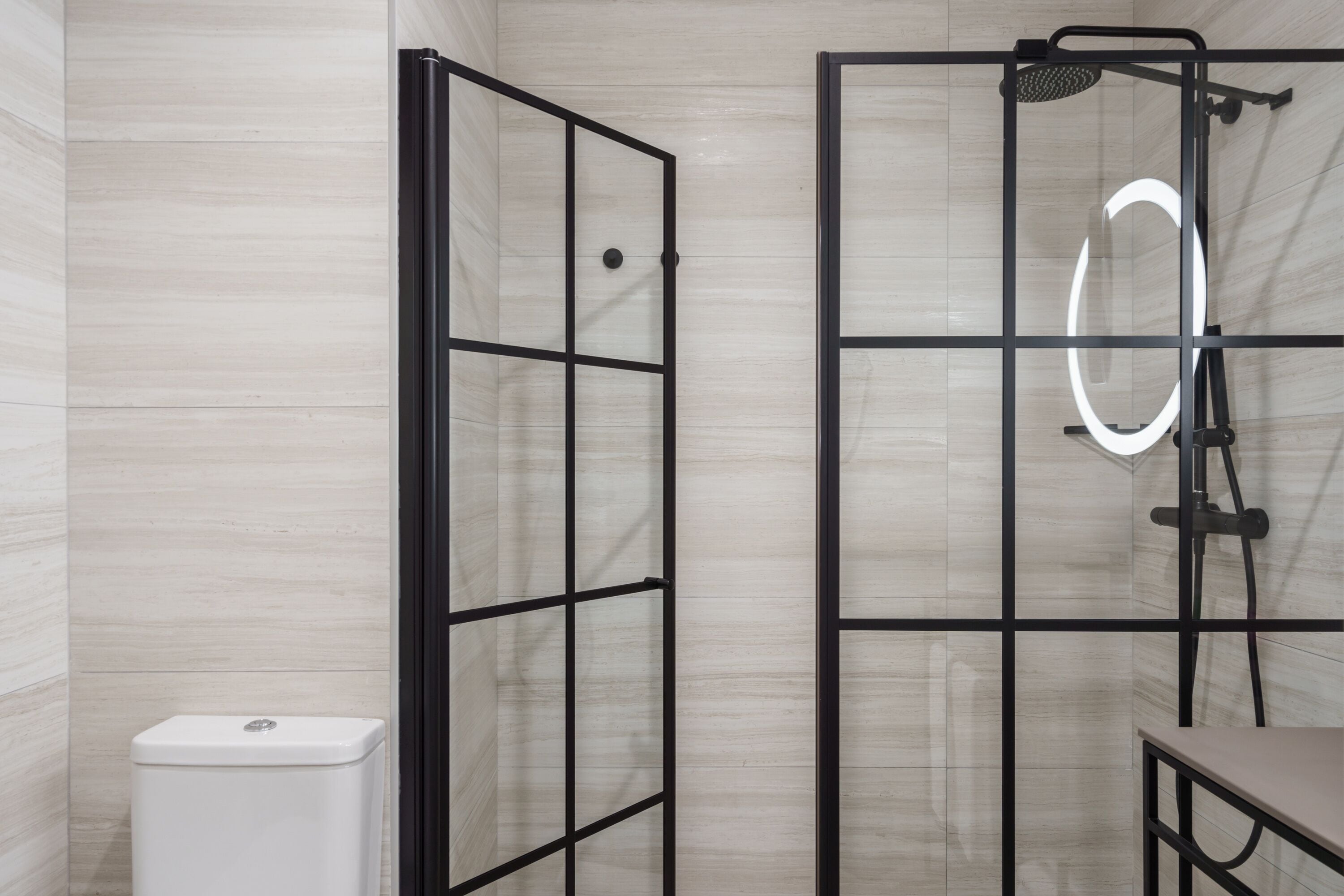 A modern bathroom with a glass shower enclosure, a toilet, and a vanity with a mirror.