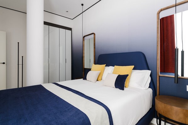 Un dormitorio moderno con una cama grande, un armario y un espejo.