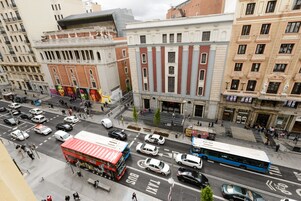 Eine belebte Stadtstraße mit einem roten Doppeldeckerbus, einem blauen Bus und mehreren Autos.