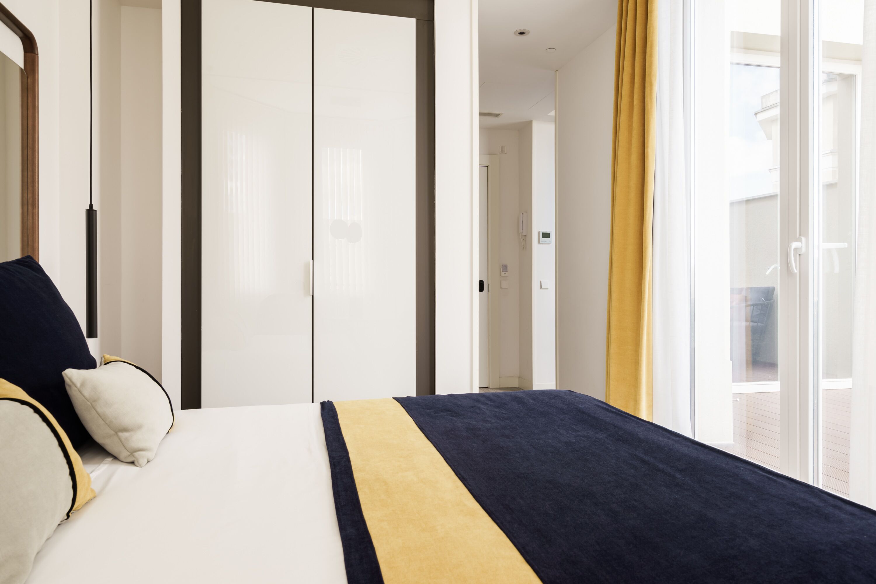 A hotel room with a bed, a wardrobe, and a window with curtains.