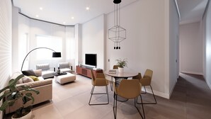 Un salon moderne comprenant un canapé, un téléviseur, une table à manger, des chaises et une plante en pot.