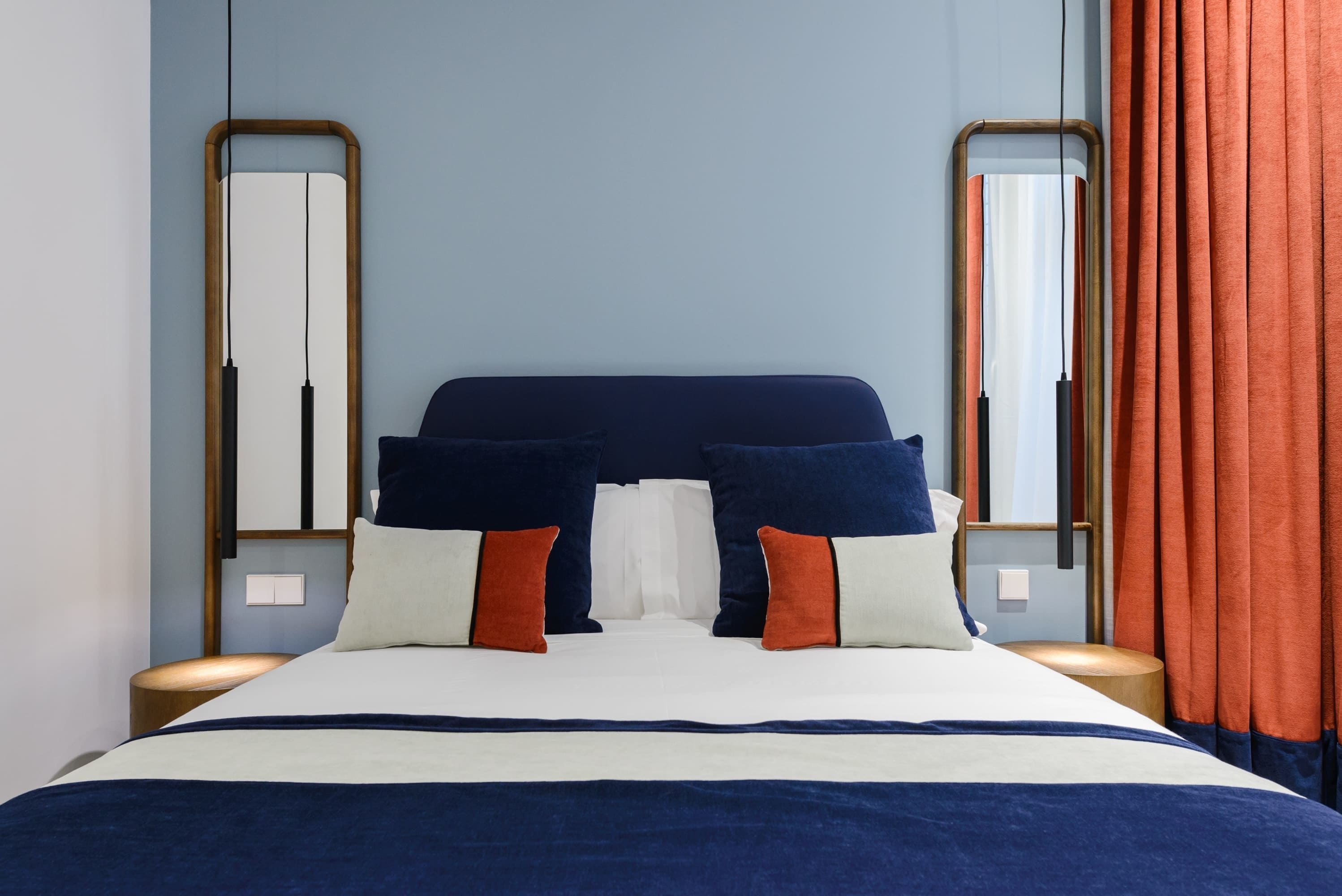 A bed with a dark headboard, white bedding, and two side tables with lamps.