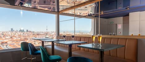 A restaurant with a city view, tables, and chairs.