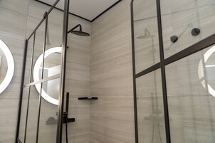 Ein modernes Badezimmer mit einer Duschkabine aus Glas, einem runden Spiegel und einem minimalistischen Design.