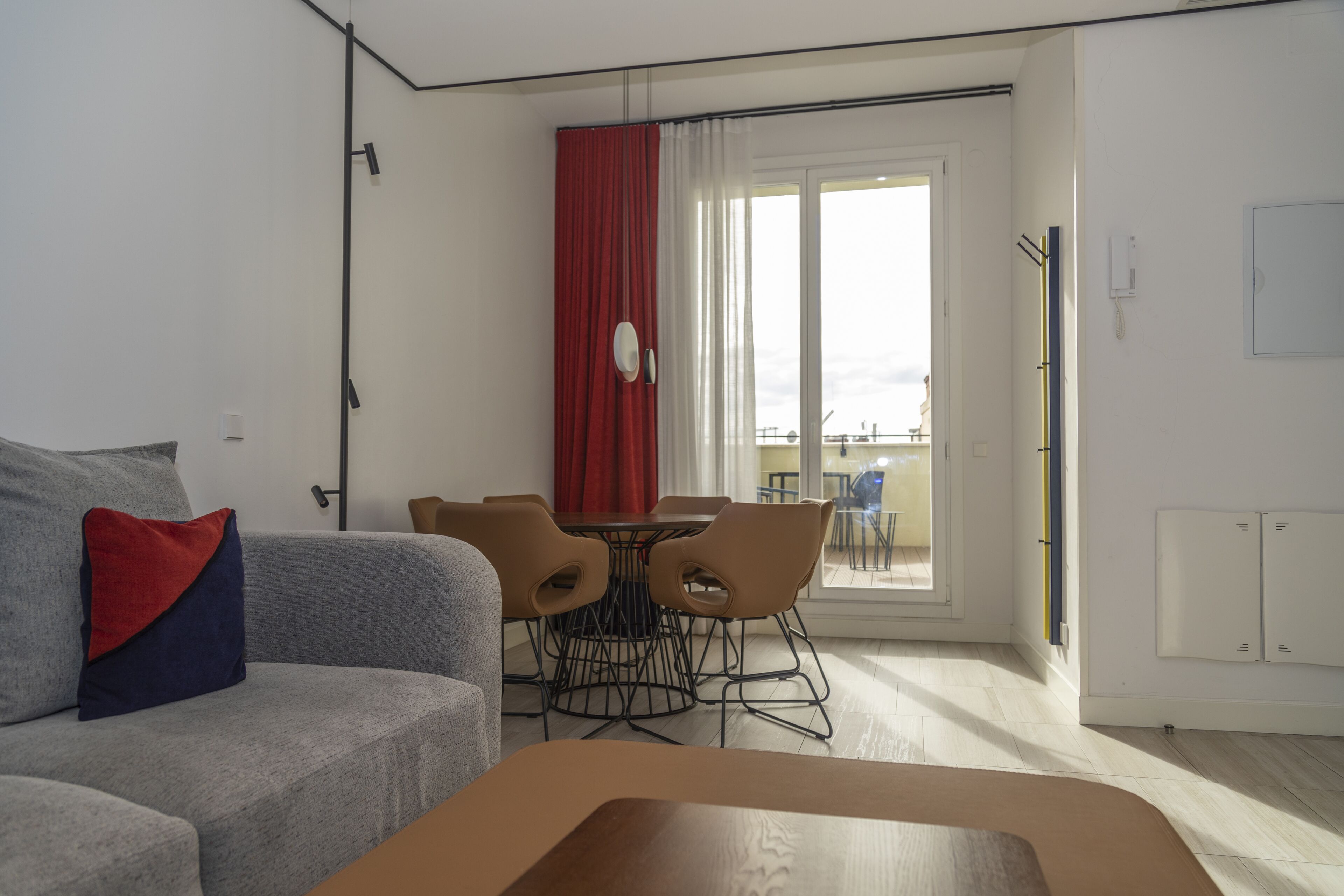 A modern living room with a grey sofa, a wooden coffee table, and a dining area with a round table and chairs.
