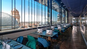 Un restaurant offrant une vue sur un dôme et le paysage urbain grâce à de grandes fenêtres.